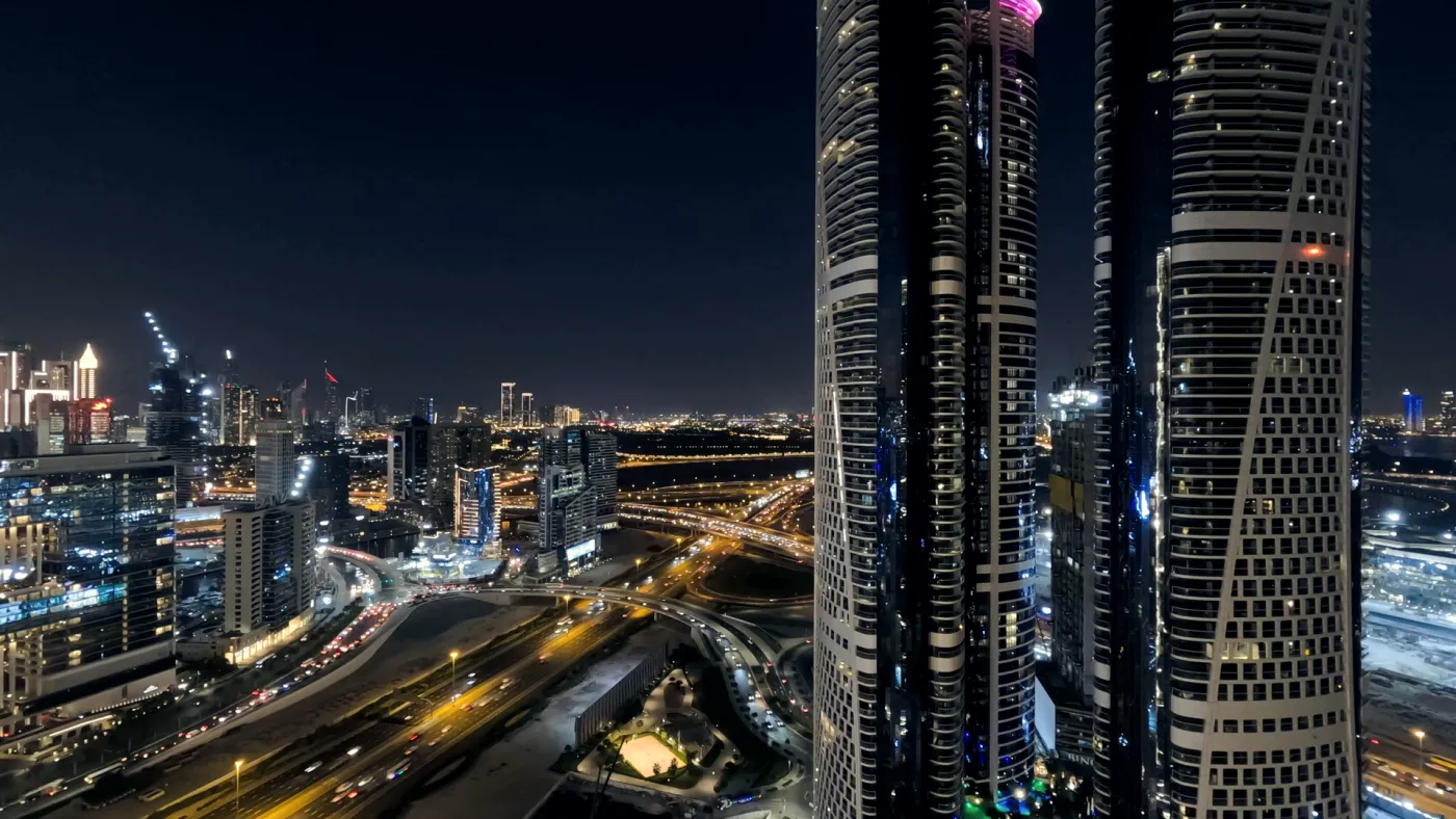 Dubai business district at night from above, towers beside a lit motorway